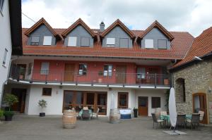 a large building with a balcony and tables and chairs at Hofgut Metzler in Gau-Heppenheim