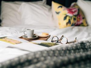 a tray with glasses and a cup of coffee on a bed at Clandeboye Lodge Hotel in Bangor