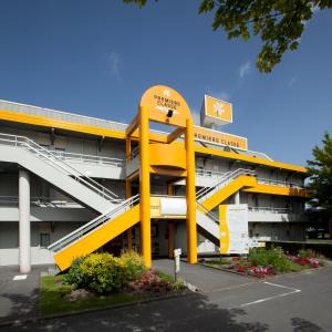 a large yellow building with a staircase in front of it at Premiere Classe Besancon Ecole Valentin in Besançon