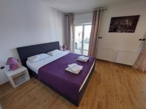 a bedroom with a large bed with a purple blanket at Apartments Daniel in Vodice