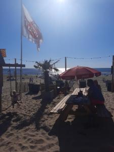 two people sitting under an umbrella on the beach at Huize Visser in Egmond aan Zee