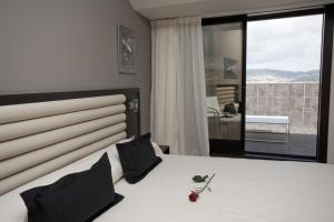 a bedroom with a large white bed with black pillows at Hotel Bienestar Moaña in Moaña
