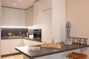 a kitchen with white cabinets and a black counter top at Petra Apuana Luxury Apartment in Pietrasanta