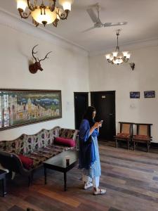 Kobieta stojąca w salonie patrząca na komórkę w obiekcie The Fateh Hotel by Le Pension Stays w mieście Udaipur