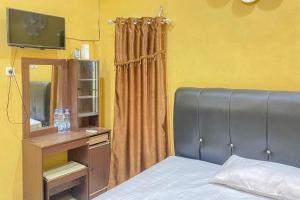 ein Schlafzimmer mit einem Bett und einem TV auf einem Tisch in der Unterkunft Home Stay Mulyawan Syariah Sengkang Mitra RedDoorz in Singkang