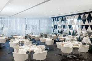 a dining room with white tables and chairs at NH Collection Berlin Mitte Friedrichstrasse in Berlin