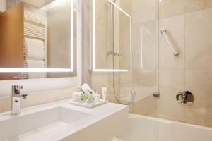 a white bathroom with a shower and a sink at NH Collection Berlin Mitte Friedrichstrasse in Berlin