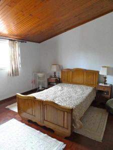 ein Schlafzimmer mit einem großen Holzbett in einem Zimmer in der Unterkunft Casa dos Pocinhos Férias tranquilas no campo in Torres Novas