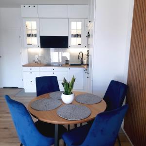 cocina con mesa de madera y sillas azules en Lux Apartment parking gratis, en Złotów