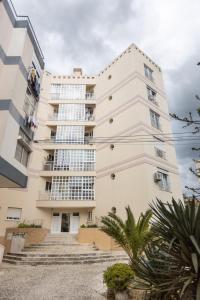a large white building with palm trees in front of it at Spacious Beach Flat in Costa Caparica by Soulplaces in Costa da Caparica