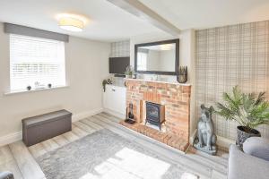 a living room with a brick fireplace with a mirror at Host & Stay - 19 West End in Hurworth