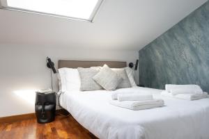 een slaapkamer met een groot bed met witte lakens en kussens bij Petra Apuana Luxury Apartment in Pietrasanta