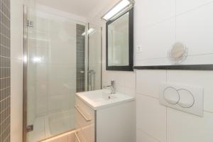 La salle de bains blanche est pourvue d'un lavabo et d'une douche. dans l'établissement Rony studio, à Split
