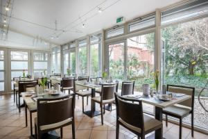 a dining room with tables and chairs and windows at Hotel am Schillerpark in Esslingen