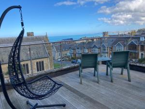 a hammock on a deck with chairs and a table at The Quies in Newquay