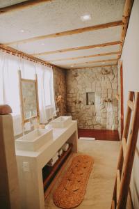 a bathroom with two sinks and a stone wall at Pousada Jardim do vento in Icaraí