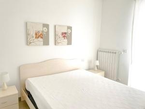 a bedroom with a white bed with three pictures on the wall at Mykonos - Cerrano Service in Pineto