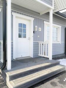 a house with a white door and a wooden porch at SANDY - Modern Row Aprt (3 rooms) - 24h Check-in in Närpiö