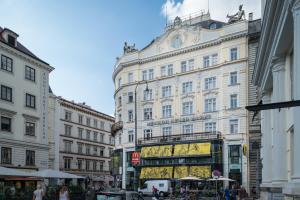 a large white building on a busy city street at Pension Neuer Markt in Vienna