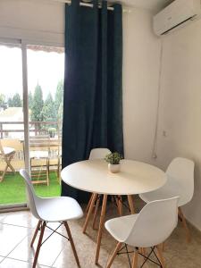 mesa y sillas en una habitación con ventana en Apartamento tropical con piscina cerca de la playa en Torremolinos
