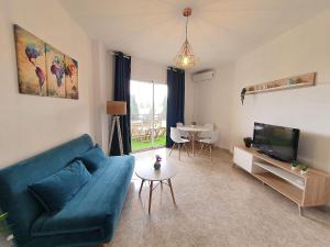 sala de estar con sofá azul y TV en Apartamento tropical con piscina cerca de la playa en Torremolinos