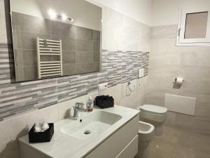 ein Badezimmer mit einem Waschbecken, einem WC und einem Spiegel in der Unterkunft Sunnyside Apartment in Torre Grande