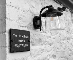 una señal en una pared de ladrillo con una luz en ella en The Old Milking Parlour, en Llandovery