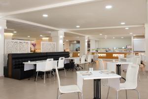 a dining room with white tables and white chairs at Olé Tropical Tenerife Adults Only in Playa de las Americas