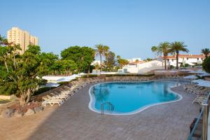 a swimming pool with lounge chairs and umbrellas at a resort at Olé Tropical Tenerife Adults Only in Playa de las Americas