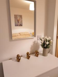 eine weiße Theke mit einer Vase aus Blumen und einem Spiegel in der Unterkunft Homebird Property - Conway House in Leeds