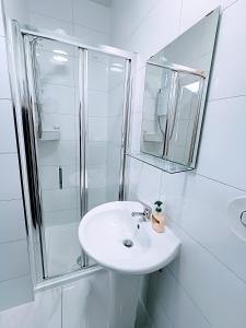 ein weißes Bad mit einem Waschbecken und einer Dusche in der Unterkunft Homebird Property - Conway House in Leeds