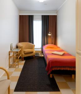 una camera d'albergo con letto e sedia di Hostel Eduskunta a Kauhajoki