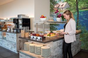 a woman standing at a counter with a plate of food at Alb Inn - Hotel & Apartments in Merklingen