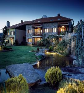 a house with a pond in front of it at El Milano Real in Hoyos del Espino