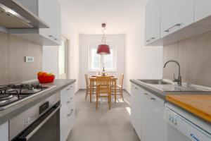 une cuisine avec des placards blancs et une table avec une salle à manger dans l'établissement Apartment Tana, à Pula