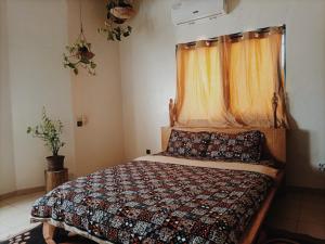 1 dormitorio con cama con edredón y ventana en Le Hublot en Cotonú