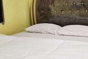 a bed with two white pillows in a room at Oma Homestay Pagar Alam Syariah RedPartner in Pagaralam +4 photos