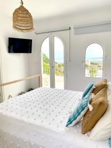 a white bedroom with a large bed with two windows at Montgo Home in Jávea