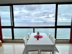 una mesa y sillas en una habitación con vistas al océano en Los Gemelos 1 - Aloturin Benidorm, en Benidorm