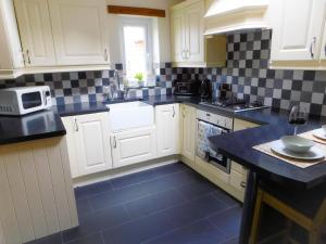 a kitchen with white cabinets and a blue tile floor at Riverdale Cottage in Rhuddlan