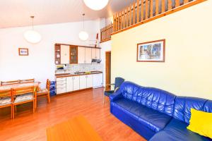 a living room with a blue couch and a kitchen at Apartment Kelly in Novalja