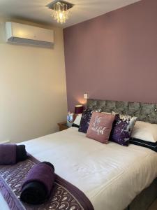 a bedroom with a large white bed with purple pillows at The Quies in Newquay