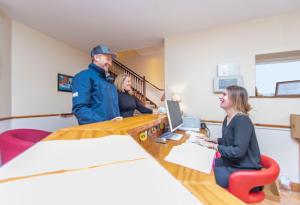 Ein Mann und zwei Frauen sitzen an einem Tisch mit einem Laptop in der Unterkunft Dingle Marina Lodge in Dingle