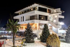 a white building with christmas trees in front of it at Hotel Le Pont in Prijedor