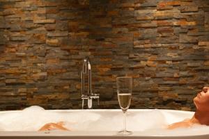 a woman sitting in a bath tub with a glass of wine at Welldone Sierpes Boutique in Seville