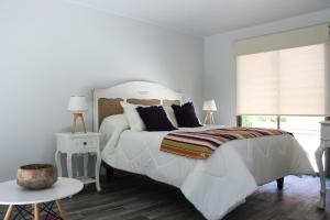 a white bedroom with a large bed and a window at Cabañas Sacramento in La Torre