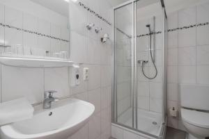 a white bathroom with a sink and a shower at Hotel Fidelio in Munich