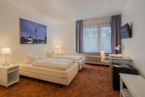 a hotel room with two beds and a desk at Hotel Fidelio in Munich