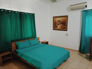 um quarto com uma cama com cortinas verdes em Le Hublot em Cotonou