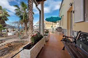 a porch of a house with a bench and an umbrella at Casa El Cardon B1 in Buenavista del Norte